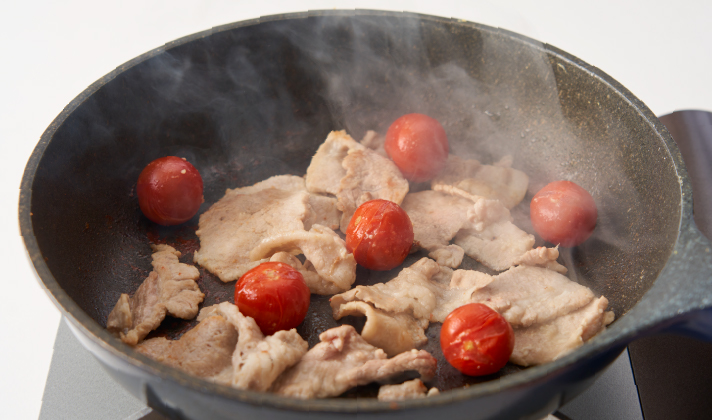 1のフライパンに豚肉とすりおろしにんにくを入れて中火で炒め、色が変わってきたらヘタを取ったミニトマトをそのまま加えてさらに2〜3分炒め、塩、こしょうで味を調え、最後にしょうゆを加えて軽く炒める。